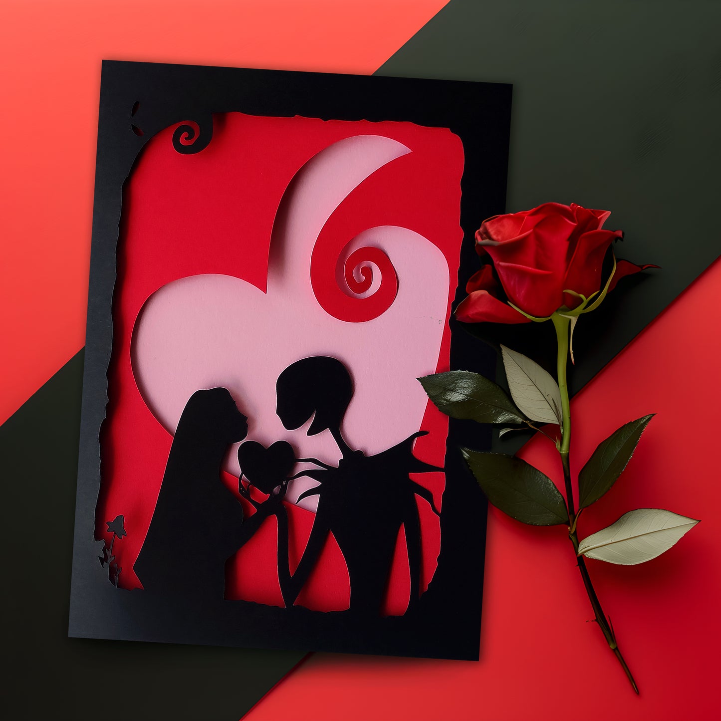 Handmade gothic romance card with black cut-out silhouette of Jack and Sally exchanging a heart, layered over a red heart with pink interior, A5 size.