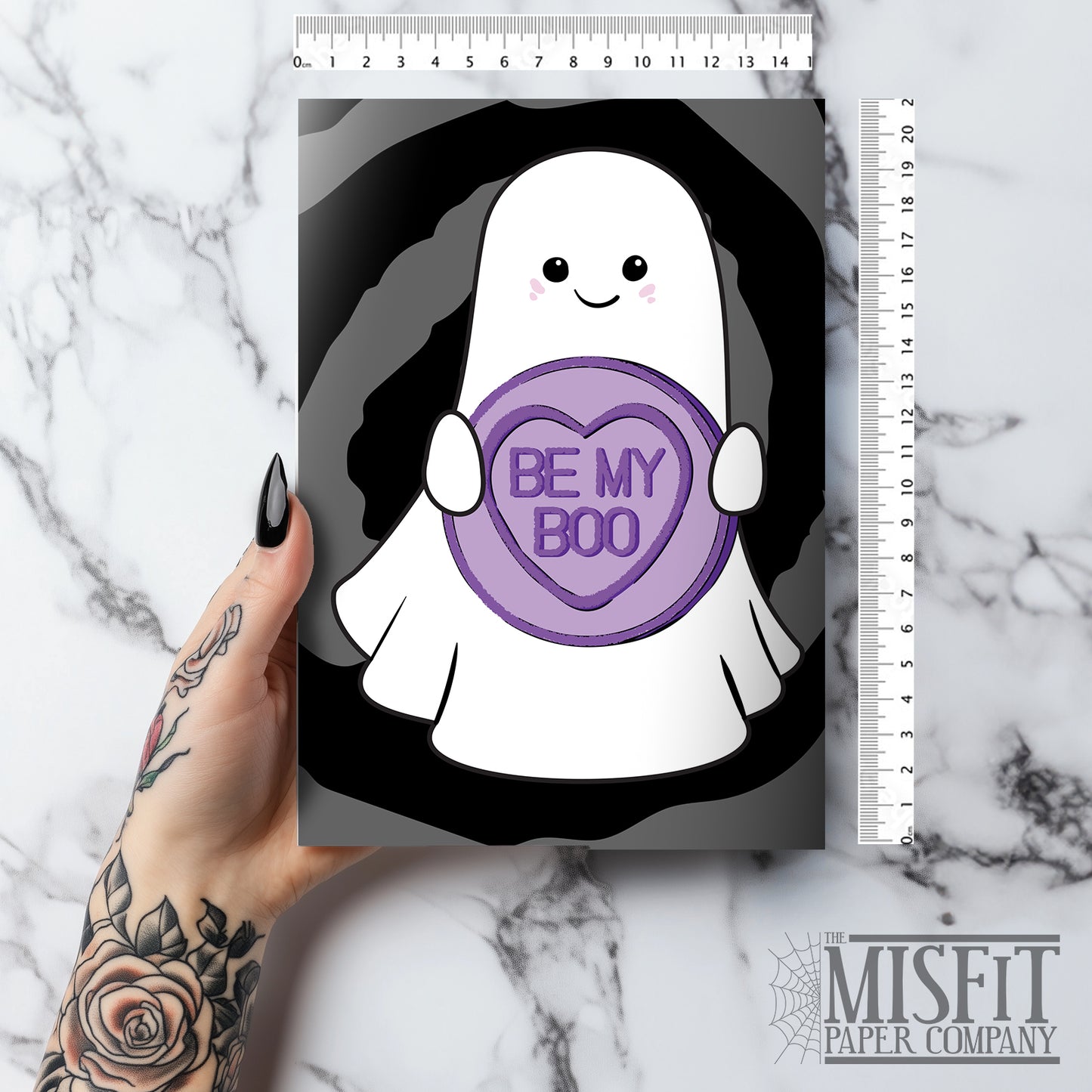 Cute gothic Valentine’s card featuring a smiling ghost holding a purple candy heart that says “Be My Boo” on a black swirl background. Includes a lilac envelope.