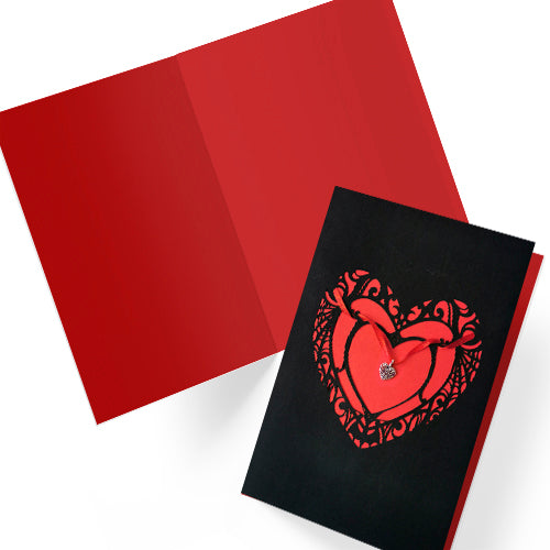 Handmade A5 black card with a red cut-out heart design and hanging silver heart charm on red ribbon. Blank white interior with envelope included. Perfect for gothic weddings, anniversaries, or alternative Valentine’s Day.