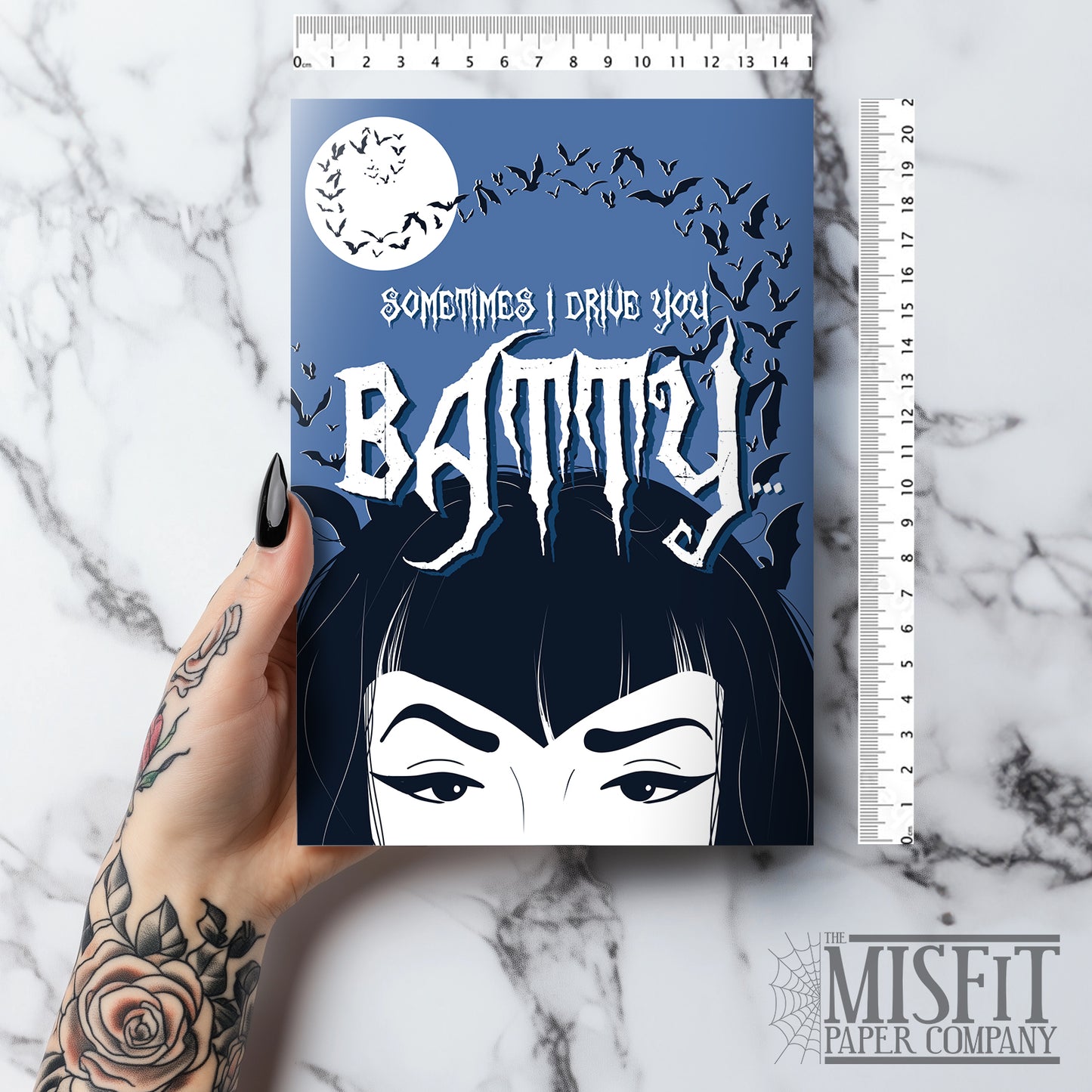 A large glossy A5 greeting card designed in a vintage horror poster style. The cover features a tired mum with bats flying over her head and the phrase "Sometimes I drive you batty...". Inside reads "But I’m your favourite vampire brat", with UK or US spelling options. Comes with a white envelope.