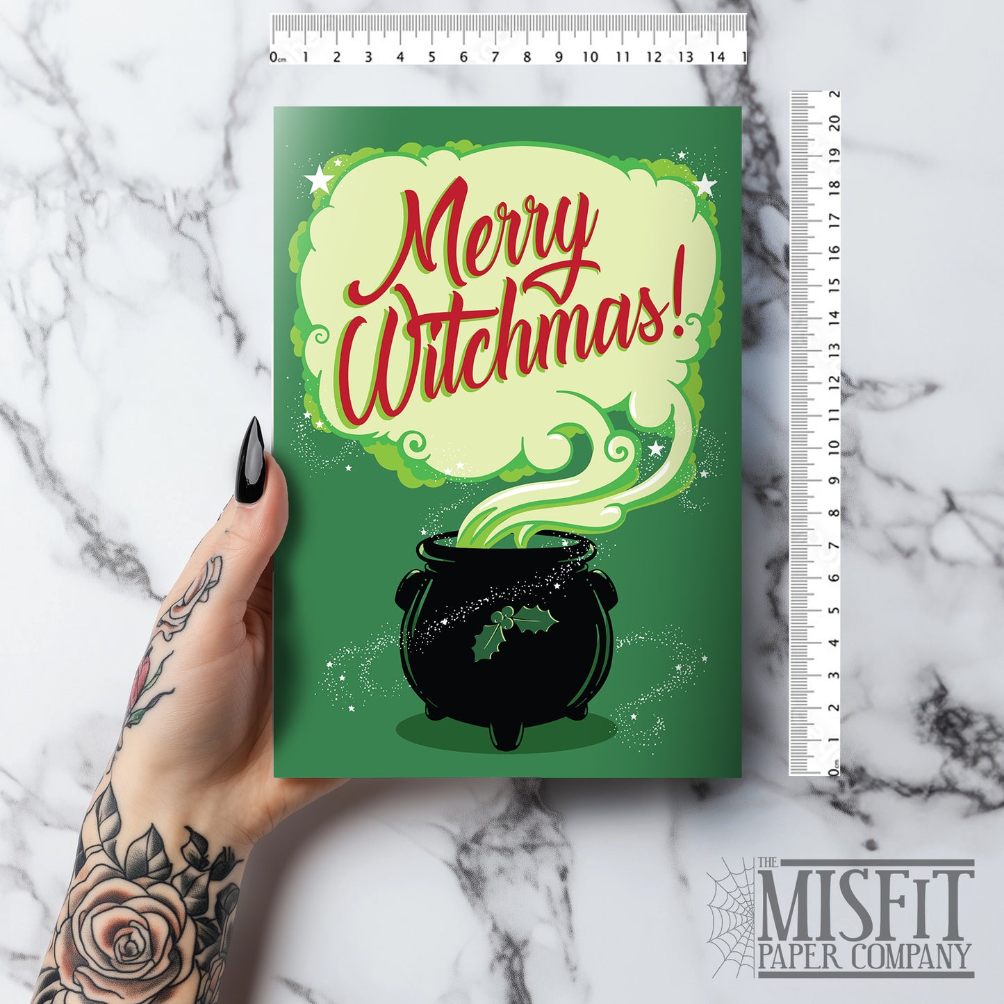 A large glossy greeting card reading "Merry Witchmas" in red, on a pale cloud of smoke from a black cauldron, all on a green background. Comes with a festive red envelope. Ideal for alternative christmas holiday.