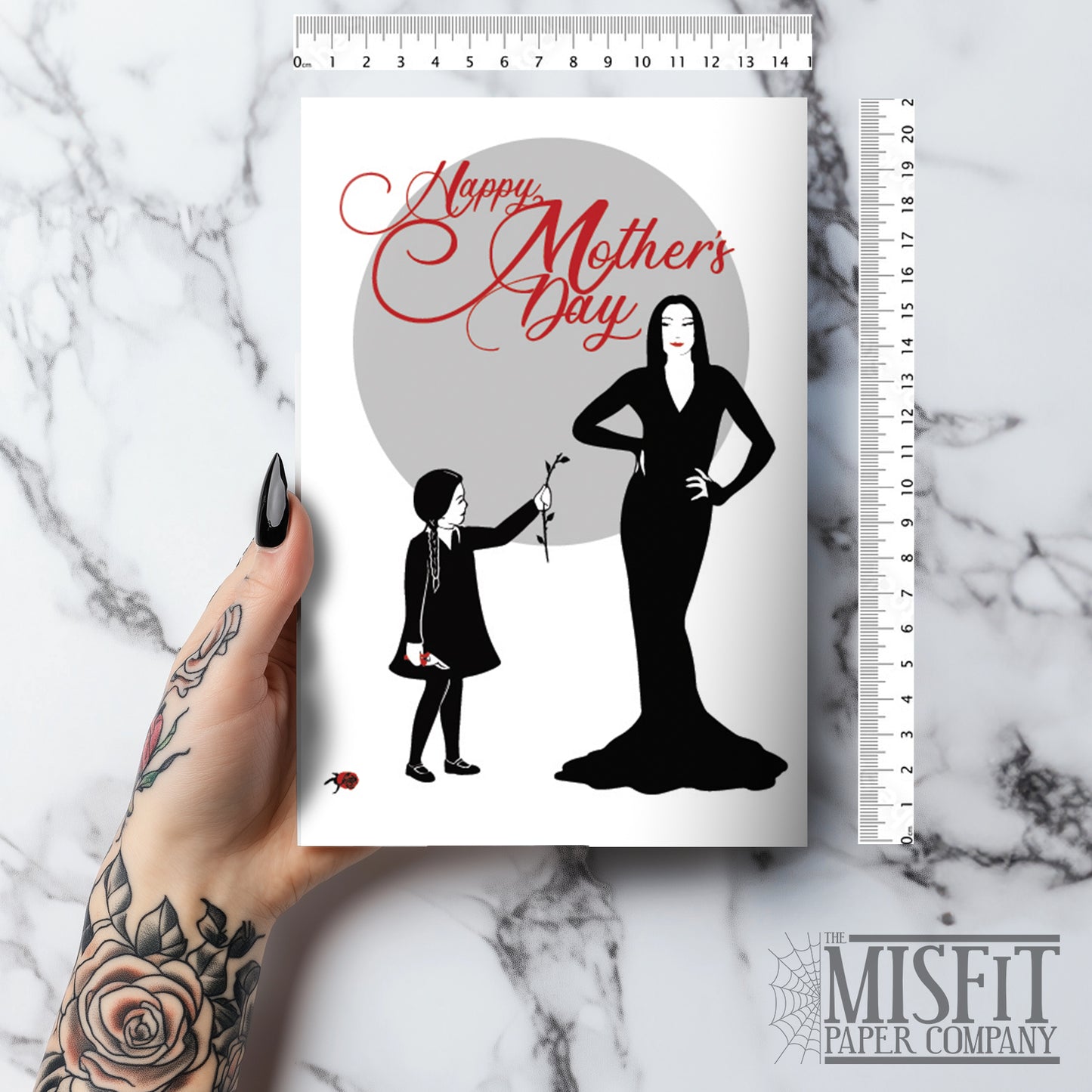 Large A5 glossy Mother’s Day card featuring Wednesday Addams giving Morticia a headless rose, with Pugsley causing mischief on the back. Includes red envelope and blank interior, perfect for spooky, gothic, and alternative mums.
