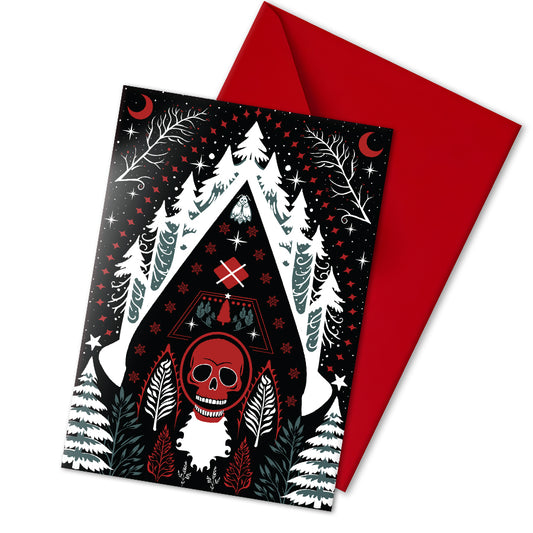 A5 glossy portrait greeting card with Scandi folk art design. Black background, white snowy pines, red crescents, stars, and a central red skull Santa motif. Graphic botanical details. Includes red envelope. Blank inside.