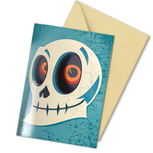A glossy blue A5 Halloween card with a skull design, featuring cut-out eyes that reveal an eerie gaze inside, styled with gothic Halloween props.