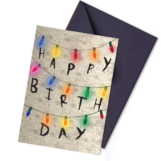 Stranger Things-inspired birthday card with fairy light lettering on a dark wall design, spelling “Happy Birthday” in a spooky, scrawled style over retro wallpaper.
