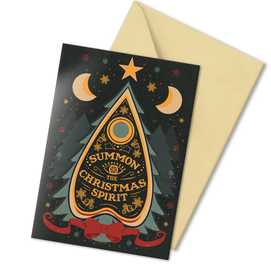 A5 glossy portrait Christmas card on black with ornate Ouija planchette reading “Summon the Christmas Spirit”, moons, stars, snowflakes and pine tree shapes with gold and green details. Cream envelope. Inside has pale green border with snowflake corners, blank area.