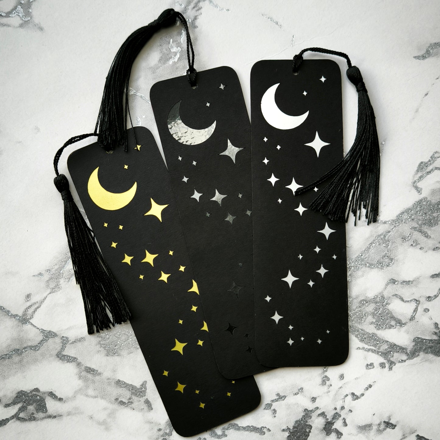 Custom gothic bookmarks with cutout names and celestial moon and star designs in red, purple, green, gold, and silver, with matching tassels