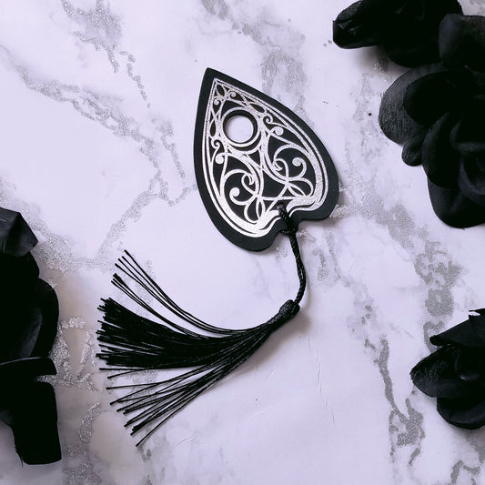 Gothic Ouija planchette bookmark with intricate silver metallic detailing and a black tassel, perfect for witchy, spooky, and alternative book lovers.