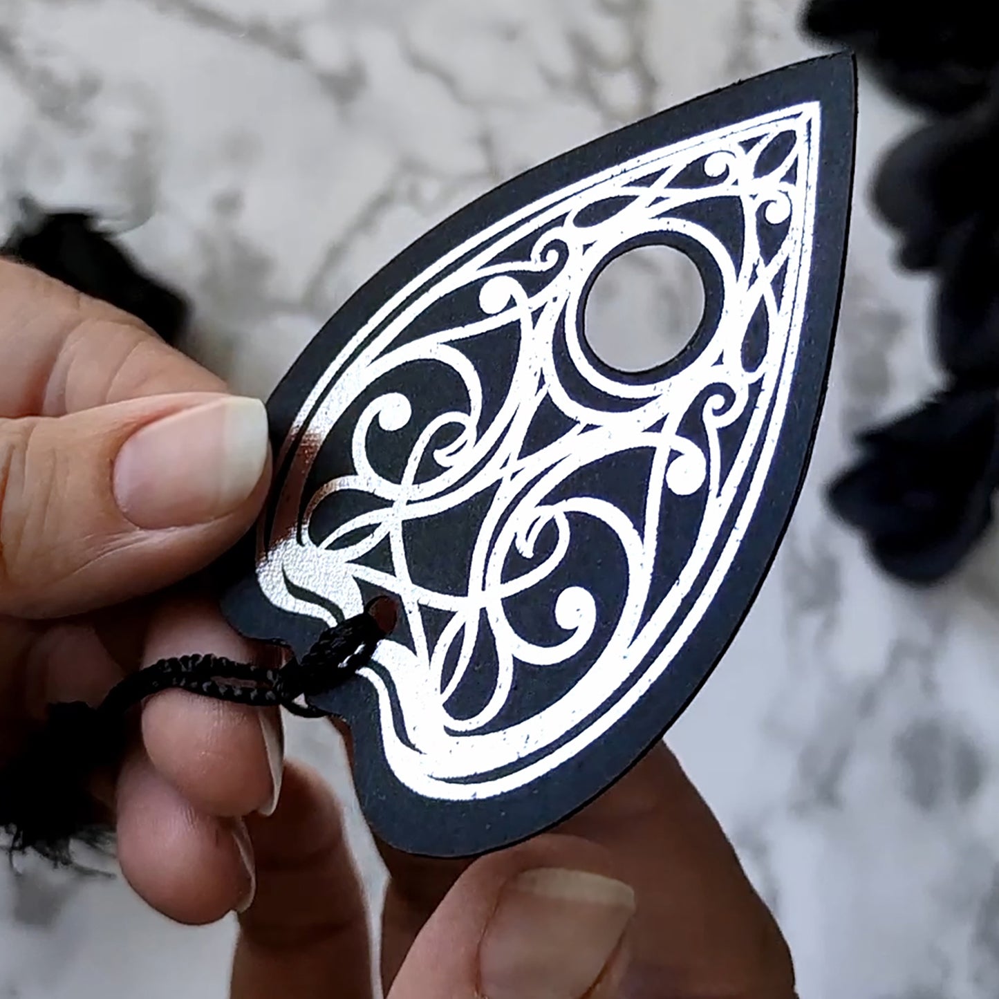 Gothic Ouija planchette bookmark with intricate silver metallic detailing and a black tassel, perfect for witchy, spooky, and alternative book lovers.