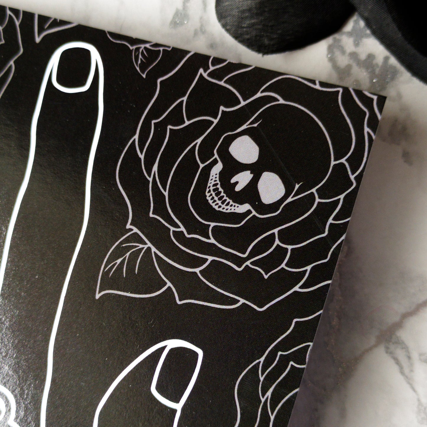 Glossy black Father’s Day card featuring a hand throwing the rock horns with skull and rose tattoos, and the phrase “My Dad Rocks” in ink lettering.