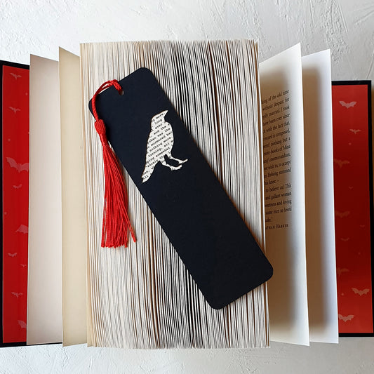 Handmade bookmark inspired by Edgar Allan Poe's poem The Raven. A raven shape cut from on each side of black card reveals a yellowed and aged section of text from the iconic horror classic, and is finished off with a silky red tassel.