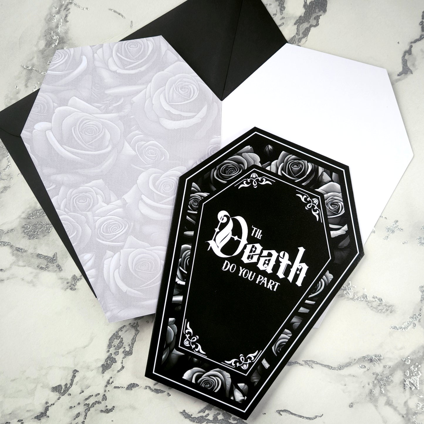 Coffin-shaped gothic wedding or anniversary card with the phrase "Til Death Do You Part" or "Til Death Do Us Part" on a black background, surrounded by monochrome roses. Subtle black and white rose inner print and a black envelope.