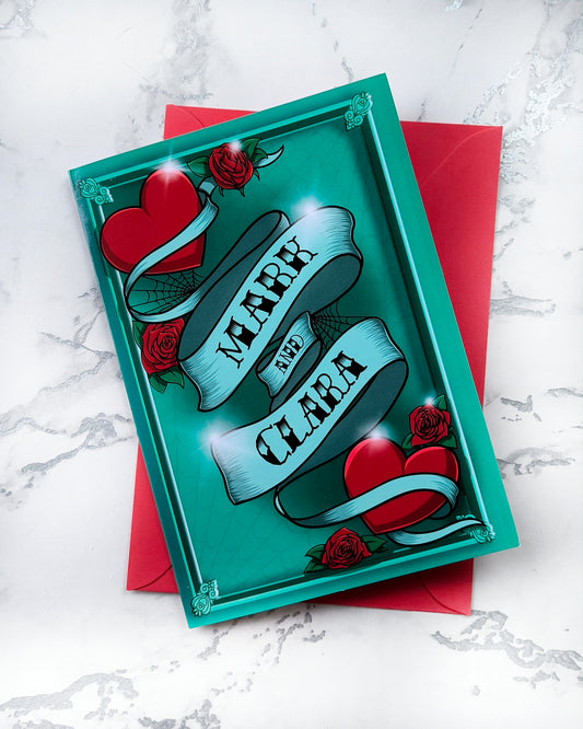 A5 personalised Valentine card in traditional tattoo style with a bold heart and banner for custom names or date, surrounded by dark linework and deep colour. Gothic romantic vibe. Blank inside with matching envelope.