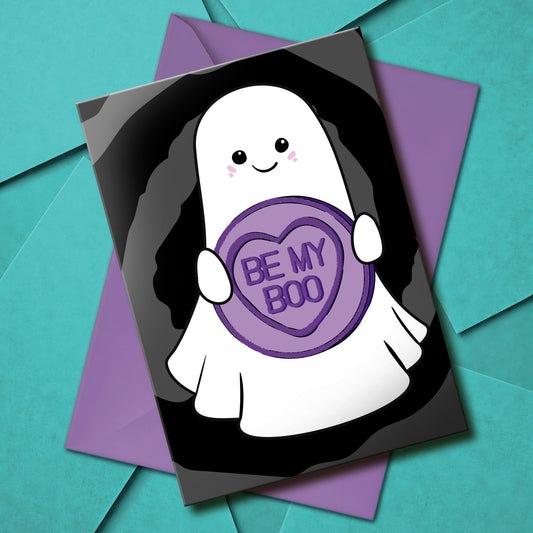 Cute gothic Valentine’s card featuring a smiling ghost holding a purple candy heart that says “Be My Boo” on a black swirl background. Includes a purple envelope.