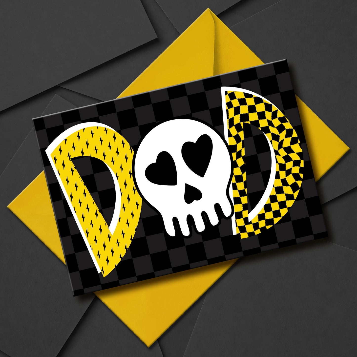 An emo-inspired greeting card with the word "DAD" in yellow and white on a black and grey checkered background. The "D"s are filled with yellow lightning bolts and checkered patterns. The "O" is a white skull with heart-shaped eyes.