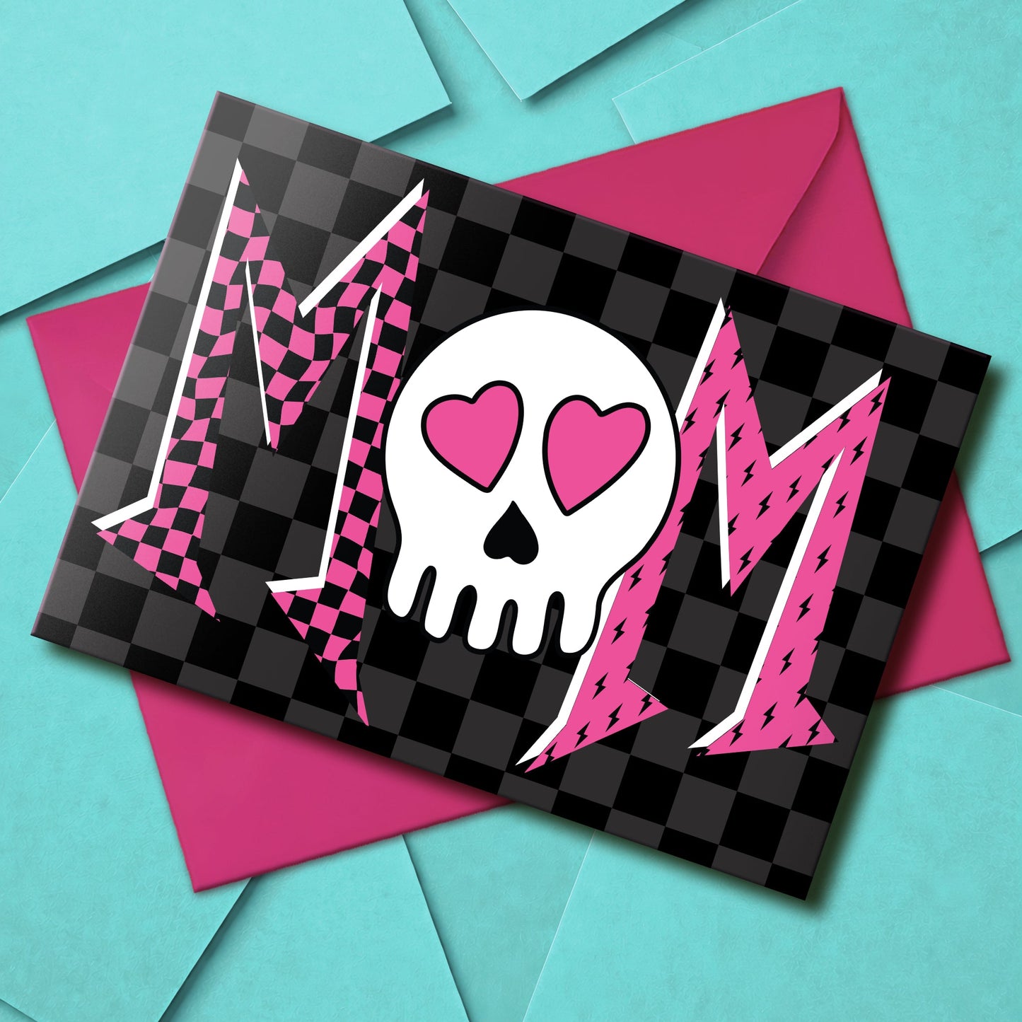 A large A5 greeting card with a black and grey checkerboard background. The bold text design features two Ms in classic emo patterns (one checkerboard, one lightning bolt) and a skull with heart eyes replacing a letter so it can read Mom, Mum, or Mam. The inside is blank with a checkerboard border. Comes with a hot pink envelope.