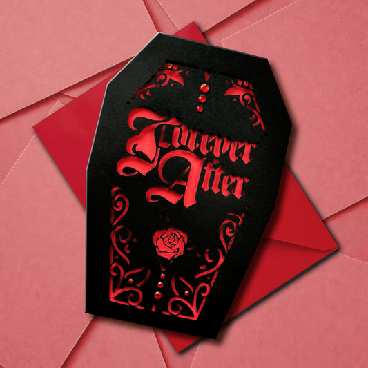 A handmade black coffin-shaped card with an intricate gothic-style design cut out to reveal a res interior. The words 'Forever After' are cut from the centre, and accentuated with subtle red gems like drops of blood. Vampire vibes for horror fans and lovers of the macabre.