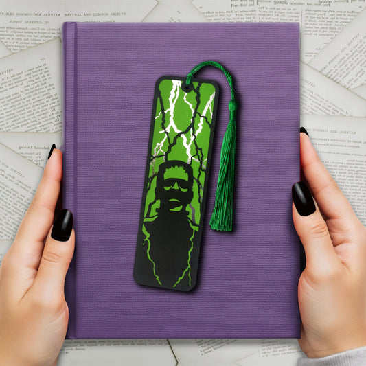 Gothic black bookmark featuring the silhouette of frankenstein's monster over a green background and silver metallic lightning strikes. Finished with a matching tassel. Perfect for horror and classic literature fans.