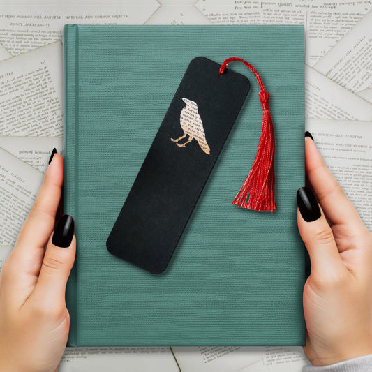 Handmade bookmark inspired by Edgar Allan Poe's poem The Raven. A raven shape cut from on each side of black card reveals a yellowed and aged section of text from the iconic horror classic, and is finished off with a silky red tassel.