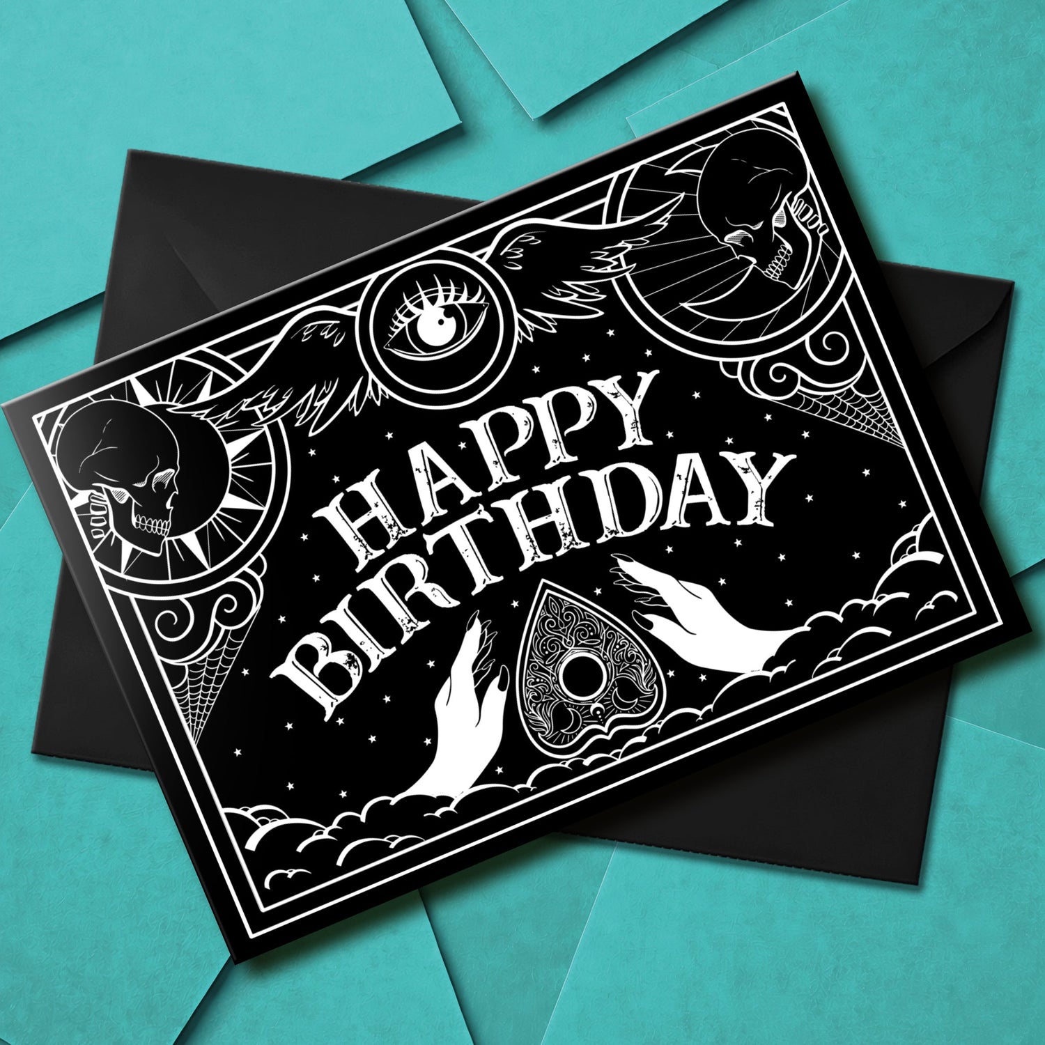 A large glossy birthday card with black and white Ouija board design and spooky lettering that reads “Have a Spooktacular Birthday,” with ornate planchette details.
