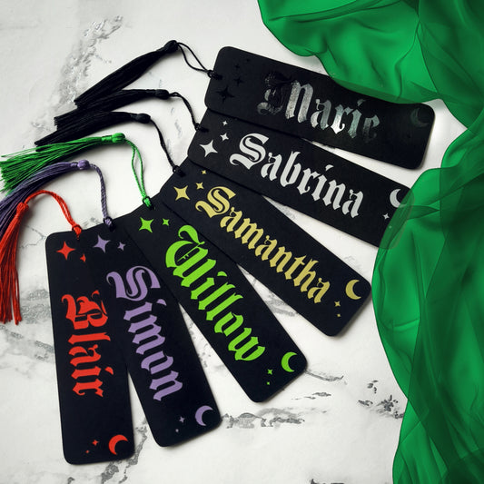 Custom gothic bookmarks with cutout names and celestial moon and star designs in red, purple, green, gold, and silver, with matching tassels