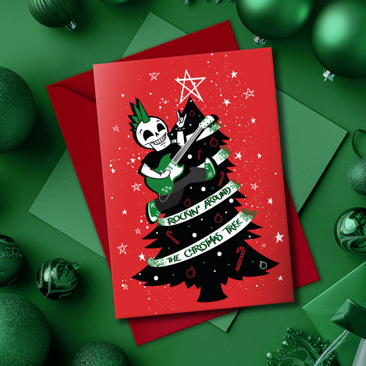 A5 glossy portrait Christmas card on red with black tree, white star and green ribbon reading “Rockin’ around the Christmas tree”. Skeleton with green mohawk plays electric guitar. Includes red envelope. Inside has small red star print with blank area.