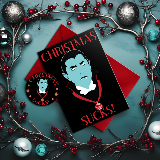 A5 glossy portrait greeting card with graphic vampire on black background, pale blue face, white eyes and fangs, red collar and bauble. Red serif text reads “CHRISTMAS SUCKS!”. Gothic, spooky style. Includes red envelope. Blank inside.