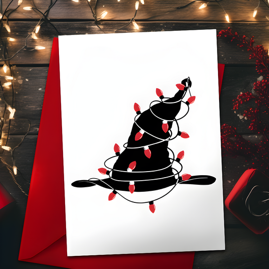 A5 glossy portrait Christmas card with minimalist black witch hat wrapped in red string lights on a white background. Clean graphic style. Includes red envelope. Blank inside.