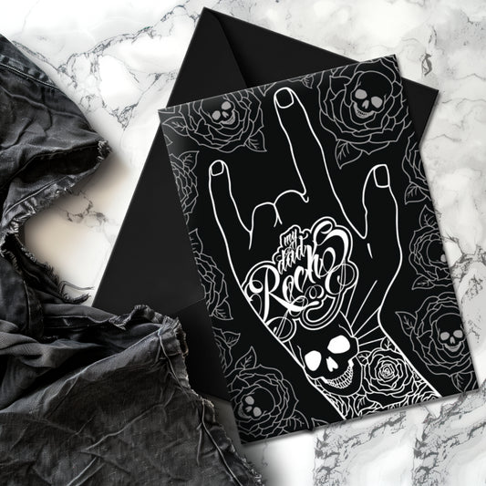 Glossy black Father’s Day card featuring a hand throwing the rock horns with skull and rose tattoos, and the phrase “My Dad Rocks” in ink lettering.