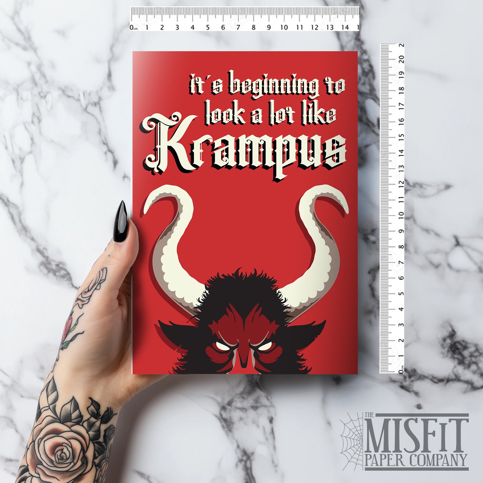 A5 glossy portrait Christmas card on red with large Krampus horns and eyes, cream gothic lettering reading “it’s beginning to look a lot like Krampus”. Small printed Krampus silhouette inside corner. Includes red envelope. Blank area for message.