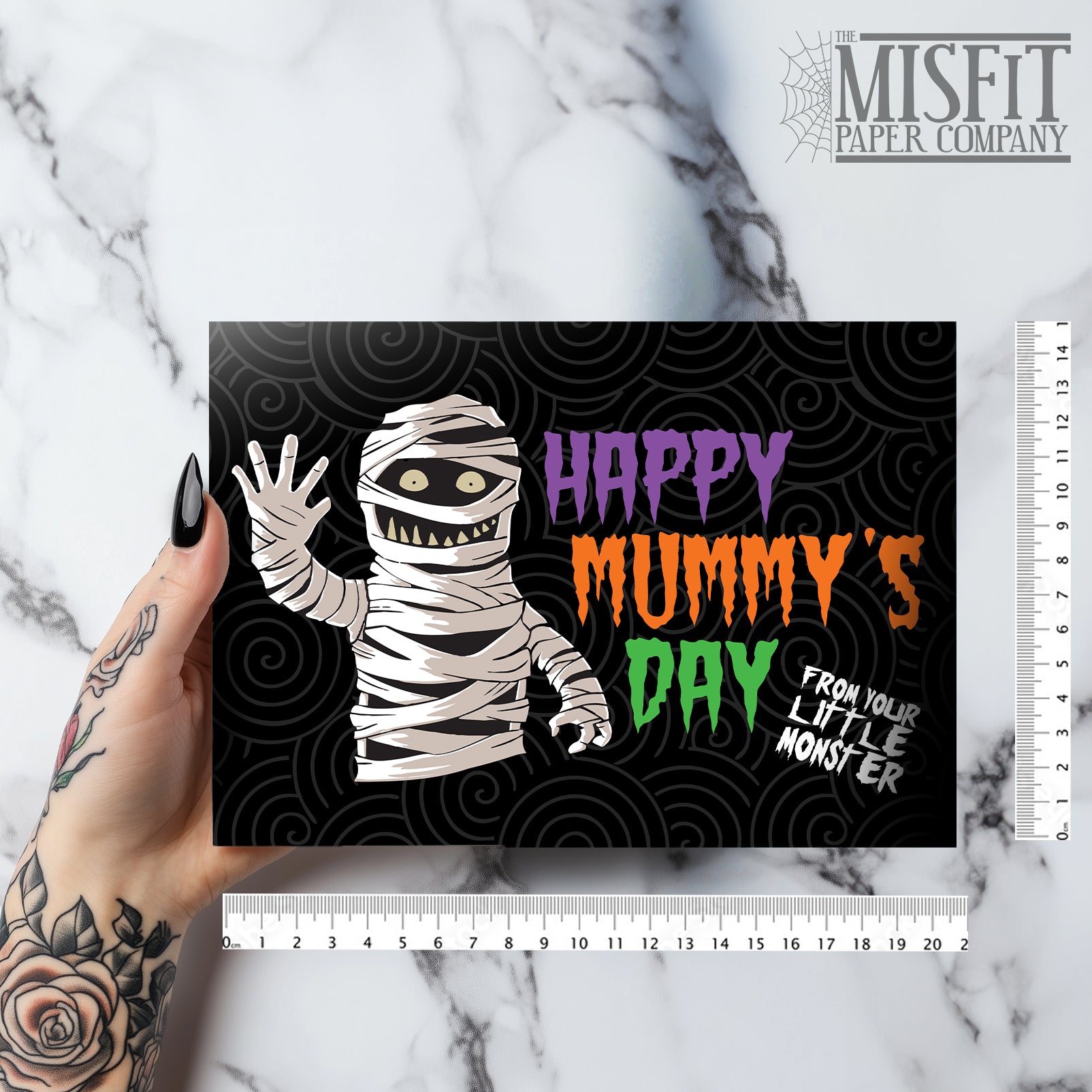 A large landscape A5 greeting card featuring a spooky cute mummy illustration with the phrase "Happy Mummy’s Day" in bold Halloween colours. The inside is decorated with a spiral motif but has no text. Comes with a bright orange envelope.