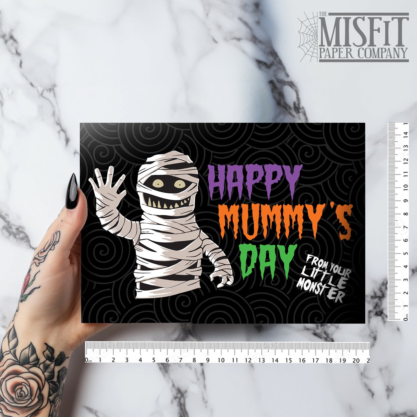 A large landscape A5 greeting card featuring a spooky cute mummy illustration with the phrase "Happy Mummy’s Day" in bold Halloween colours. The inside is decorated with a spiral motif but has no text. Comes with a bright orange envelope.