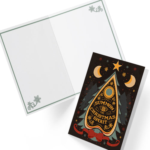 A5 glossy portrait Christmas card on black with ornate Ouija planchette reading “Summon the Christmas Spirit”, moons, stars, snowflakes and pine tree shapes with gold and green details. Cream envelope. Inside has pale green border with snowflake corners, blank area.