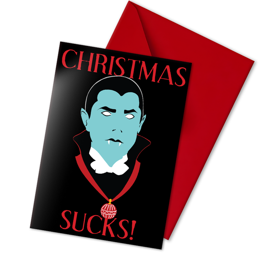 A5 glossy portrait greeting card with graphic vampire on black background, pale blue face, white eyes and fangs, red collar and bauble. Red serif text reads “CHRISTMAS SUCKS!”. Gothic, spooky style. Includes red envelope. Blank inside.