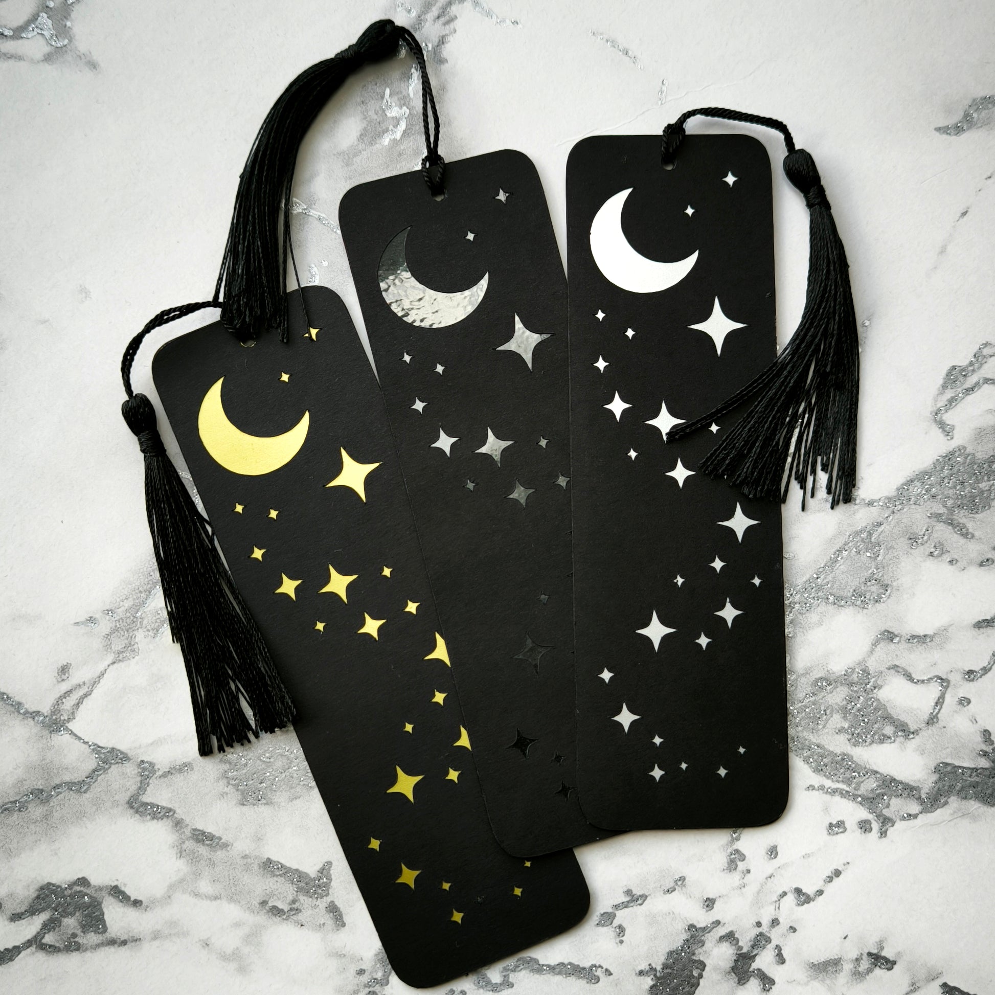 Custom gothic bookmarks with cutout names and celestial moon and star designs in red, purple, green, gold, and silver, with matching tassels