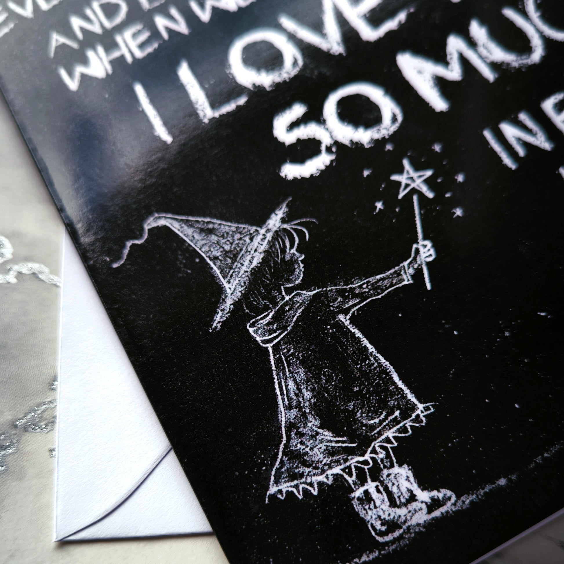 A black A5 greeting card with a chalkboard-style background, featuring a hand-drawn witch illustration casting a spell with floating love hearts. A sweet rhyming poem is written in chalk-style lettering. The card reads Happy Mother's Day inside and comes with an envelope.