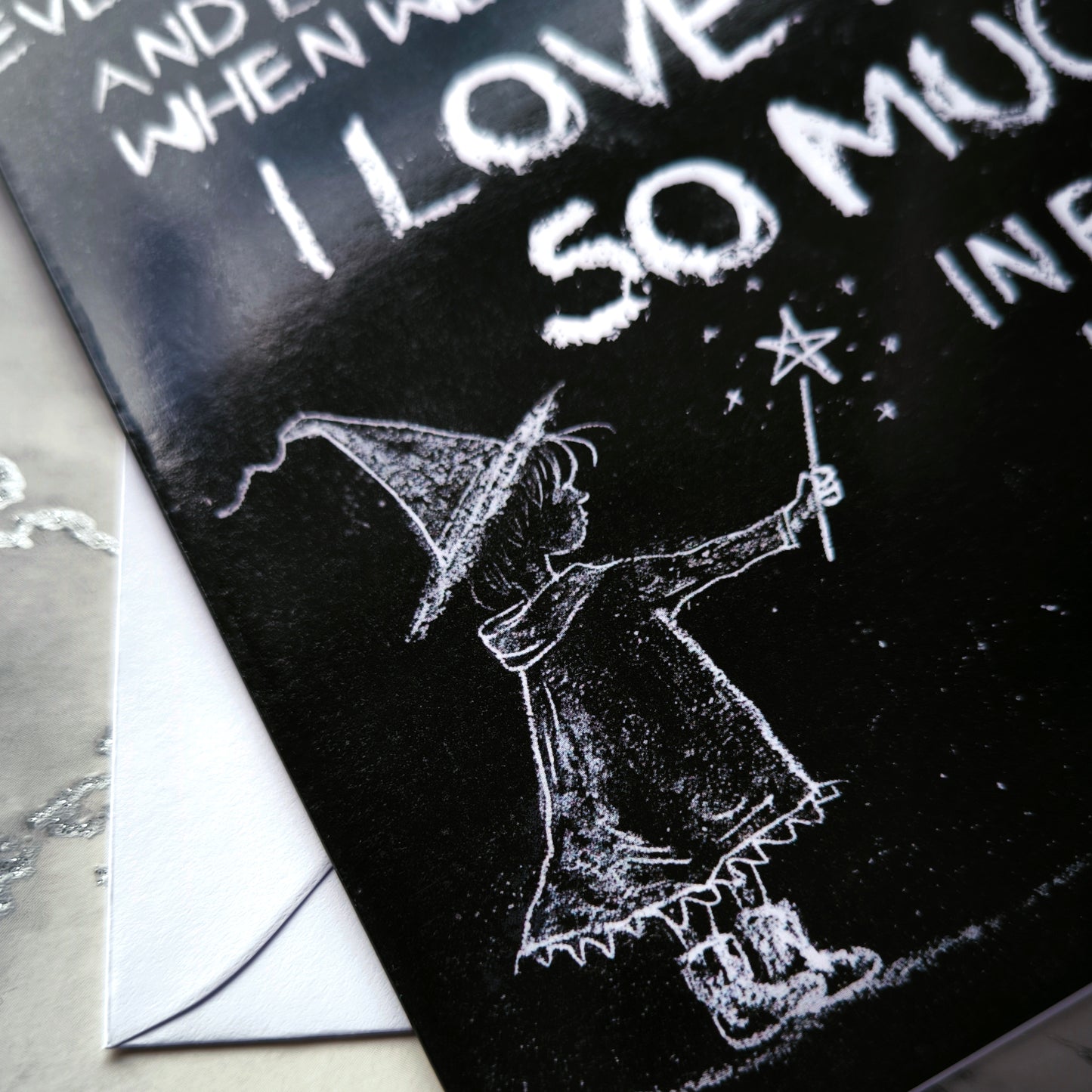 A black A5 greeting card with a chalkboard-style background, featuring a hand-drawn witch illustration casting a spell with floating love hearts. A sweet rhyming poem is written in chalk-style lettering. The card reads Happy Mother's Day inside and comes with an envelope.