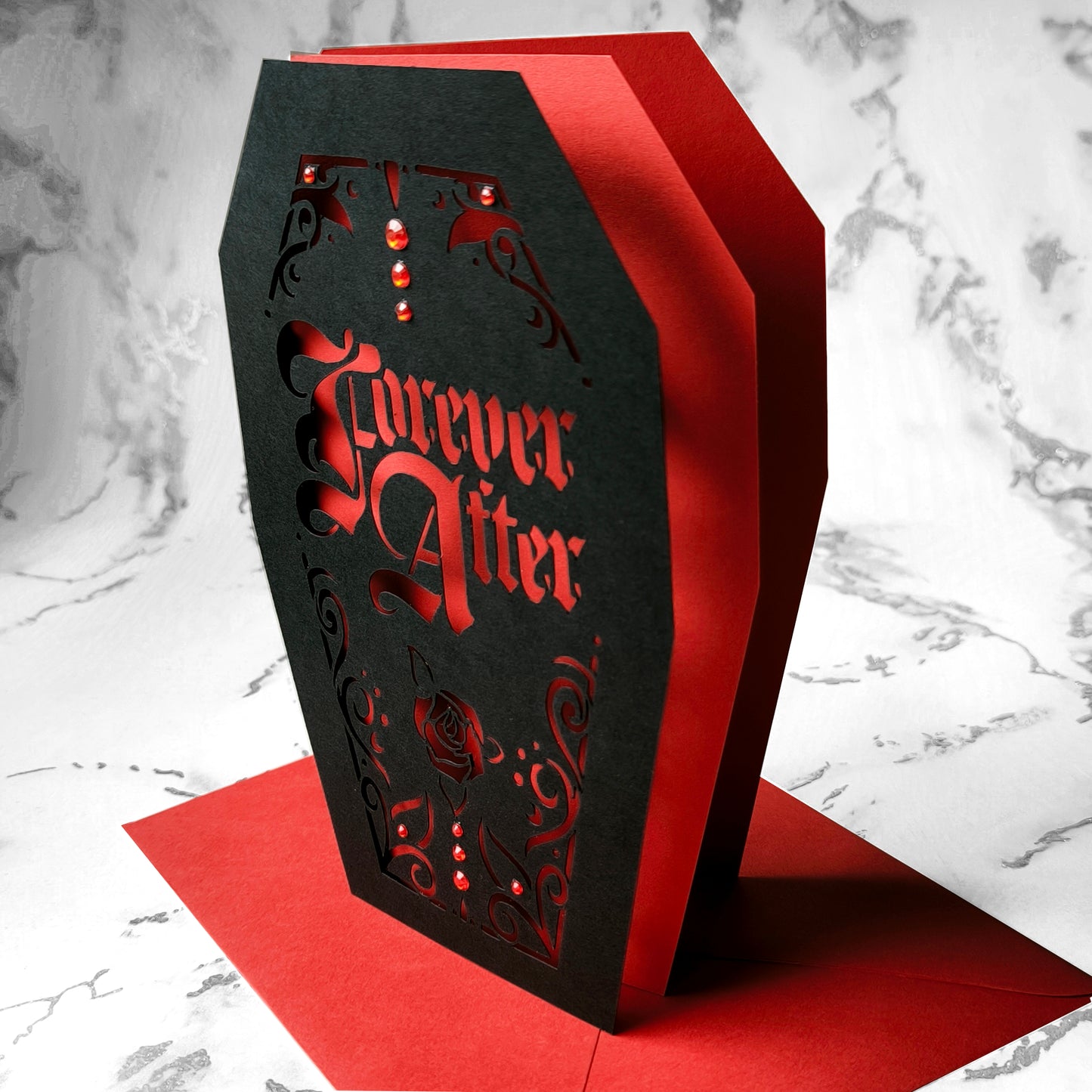 Intricately cut from rich black card with blood-red backing, this dramatic design features a blooming red rose and sparkling red gems for a touch of macabre glamour.