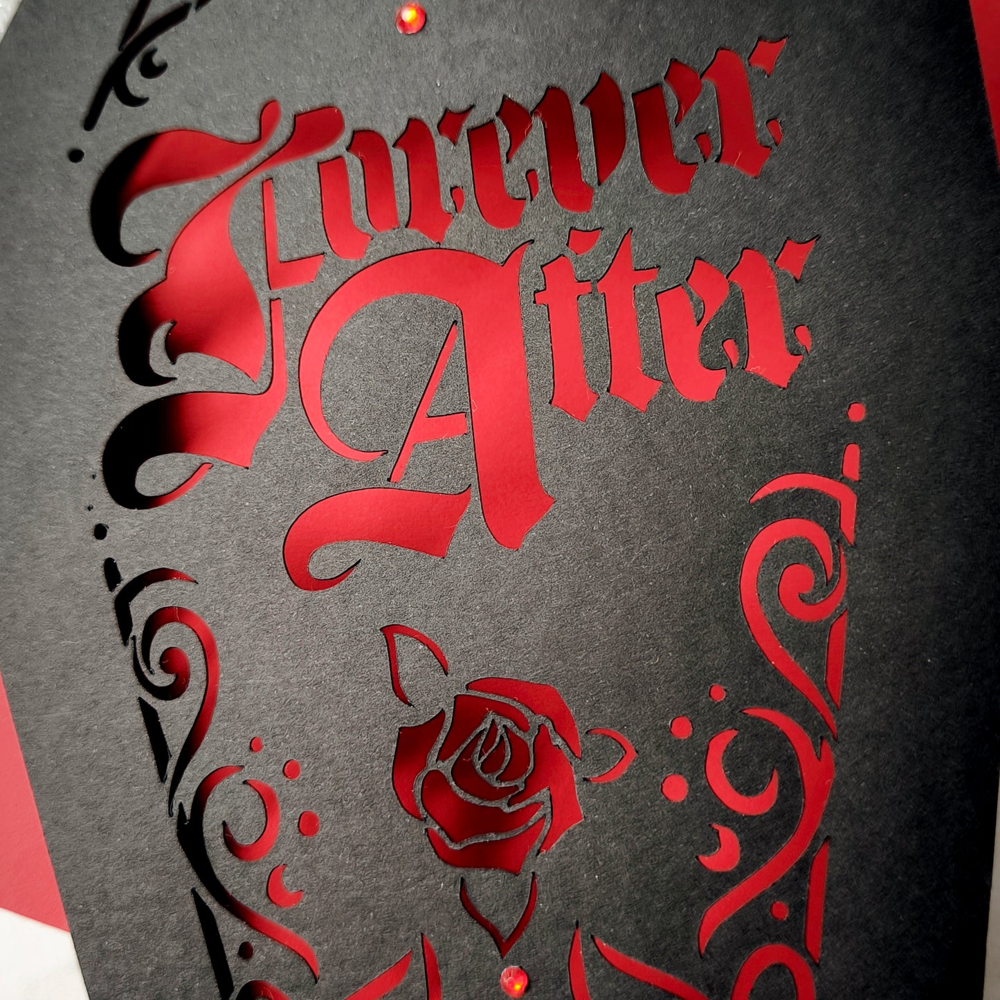 Intricately cut from rich black card with blood-red backing, this dramatic design features a blooming red rose and sparkling red gems for a touch of macabre glamour.