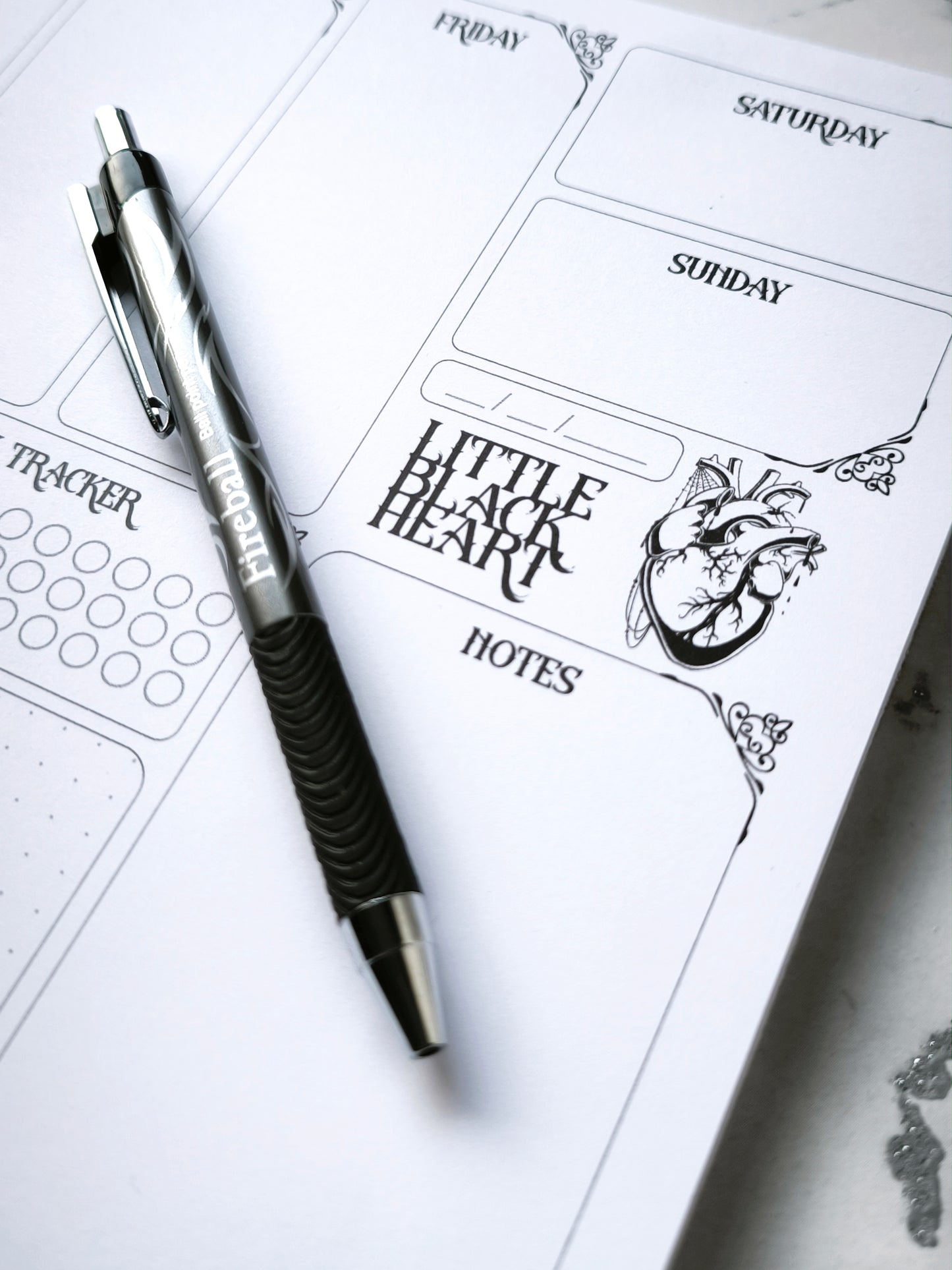 A4 undated weekly planner pad with gothic headings. Large daily boxes, to-do list, notes area, dotted section and habit tracker circles. Monochrome layout on smooth tear-off desk pad.