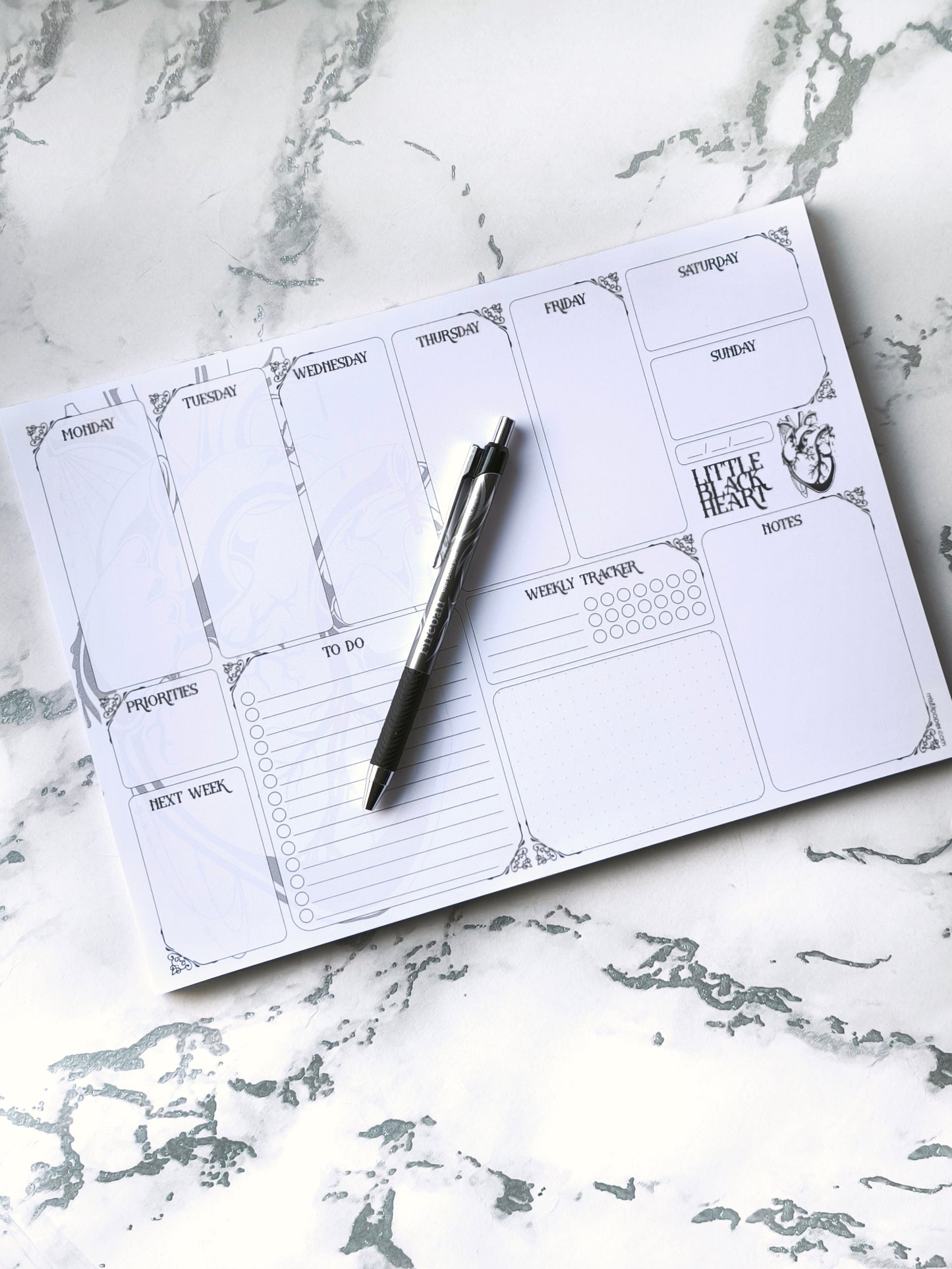 A4 undated weekly planner pad with gothic headings. Large daily boxes, to-do list, notes area, dotted section and habit tracker circles. Monochrome layout on smooth tear-off desk pad.