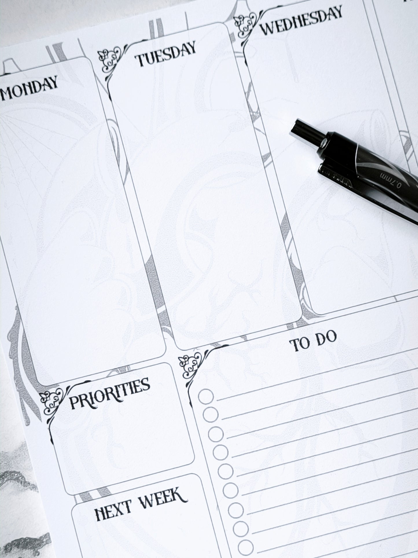 A4 undated weekly planner pad with gothic headings. Large daily boxes, to-do list, notes area, dotted section and habit tracker circles. Monochrome layout on smooth tear-off desk pad.