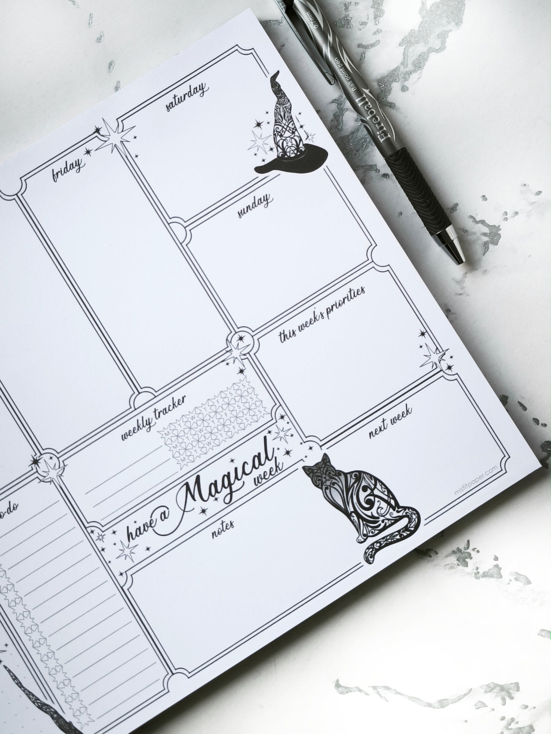 Undated weekly planner pad with black and white line-art frames and doodles. Blank boxes for each day, notes area, colouring-friendly layout. Desk pad style on smooth paper.
