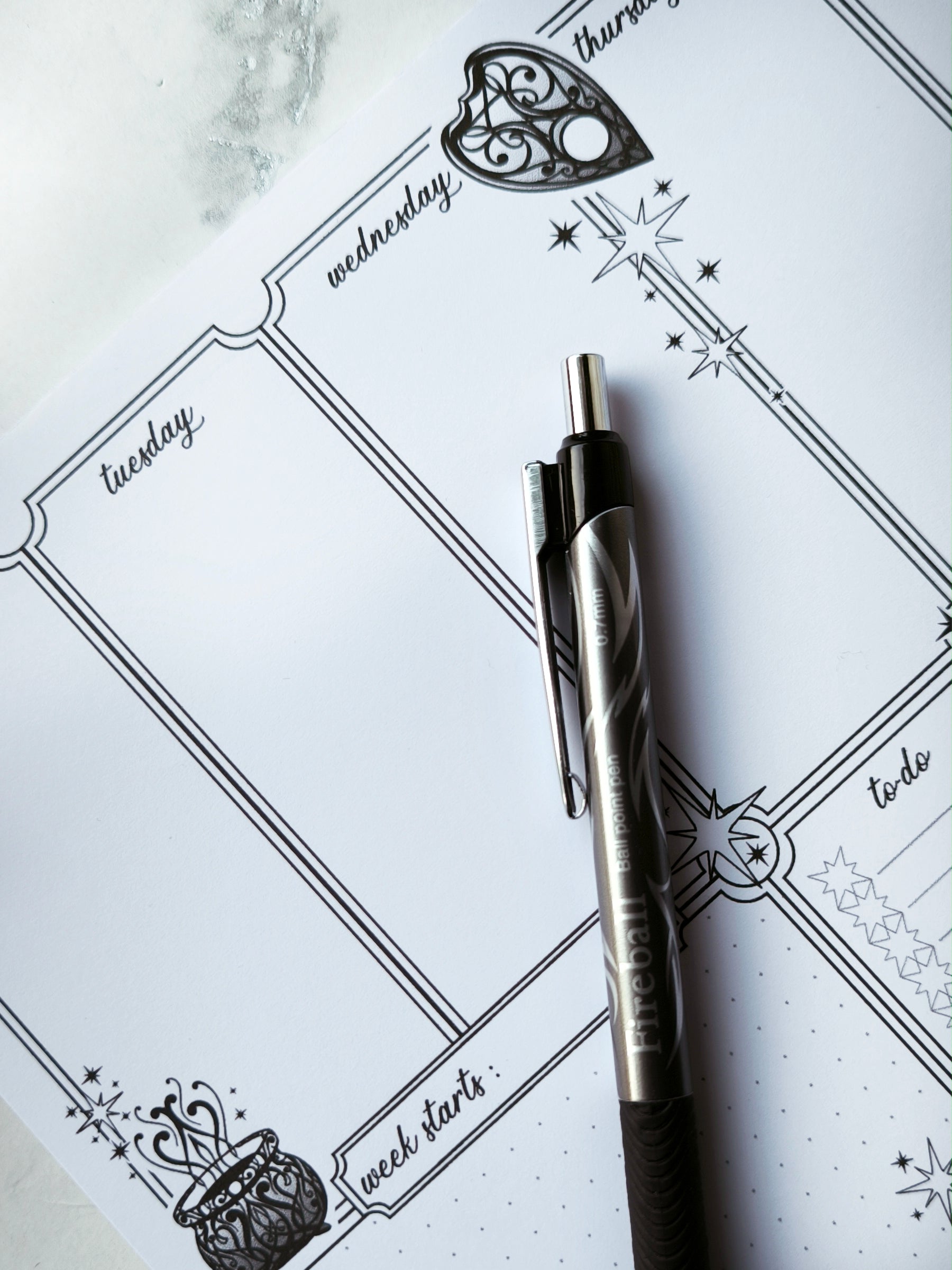 Undated weekly planner pad with black and white line-art frames and doodles. Blank boxes for each day, notes area, colouring-friendly layout. Desk pad style on smooth paper.