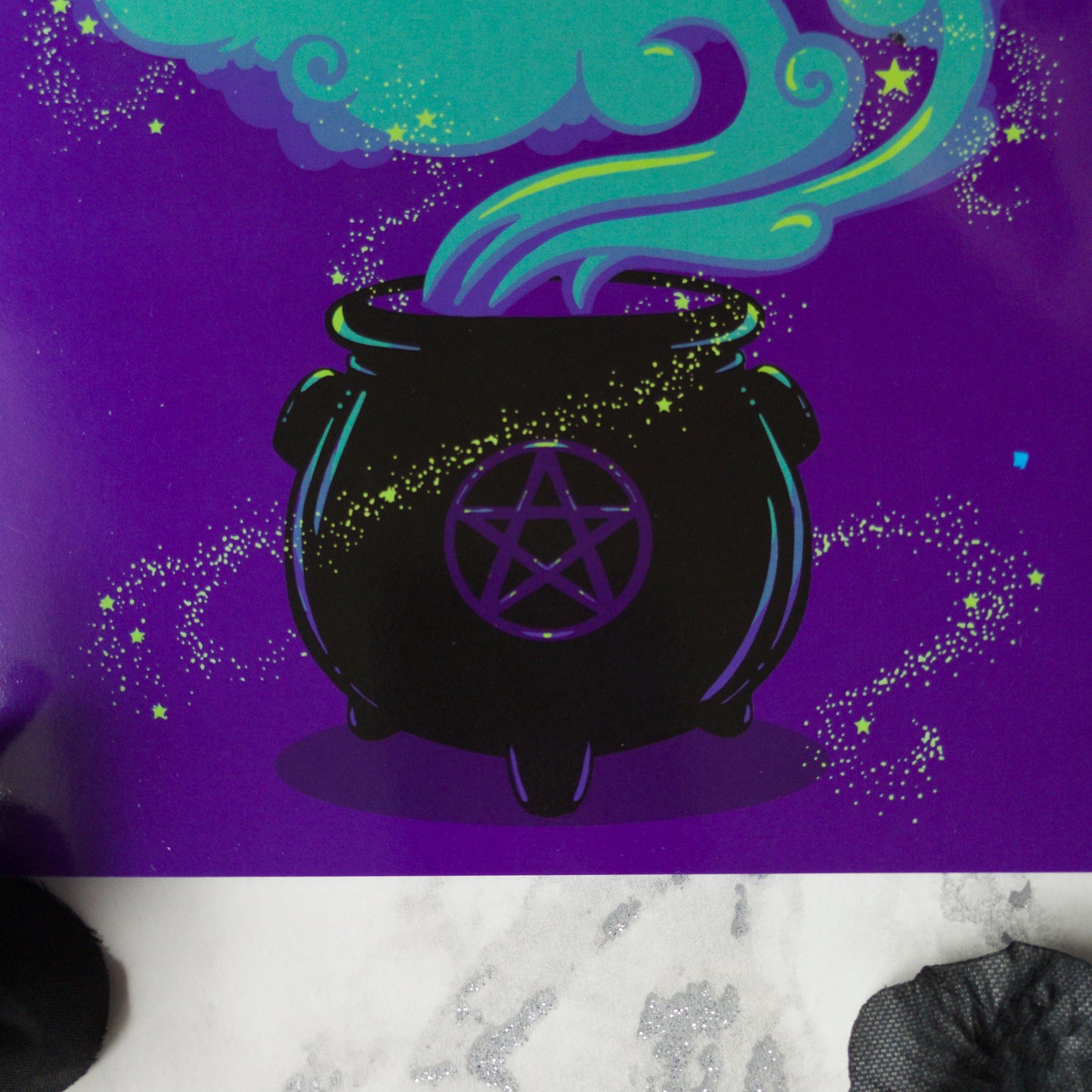 A large A5 greeting card in purple or pink, featuring a witchy cauldron illustration with billowing sparkling clouds and the words "Have a Magickal Mother’s Day." The inside has an illustration only (no text). Comes with an envelope included.