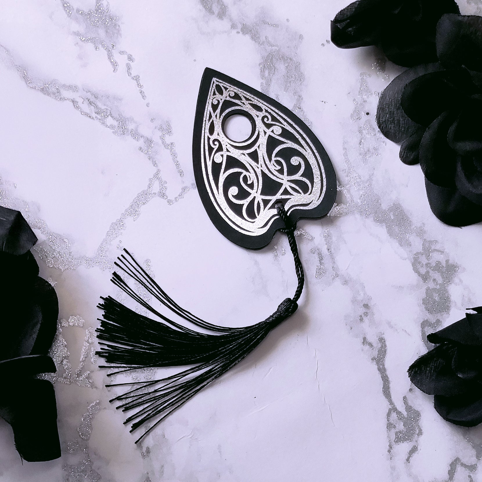 Gothic Ouija planchette bookmark with intricate silver metallic detailing and a black tassel, perfect for witchy, spooky, and alternative book lovers.