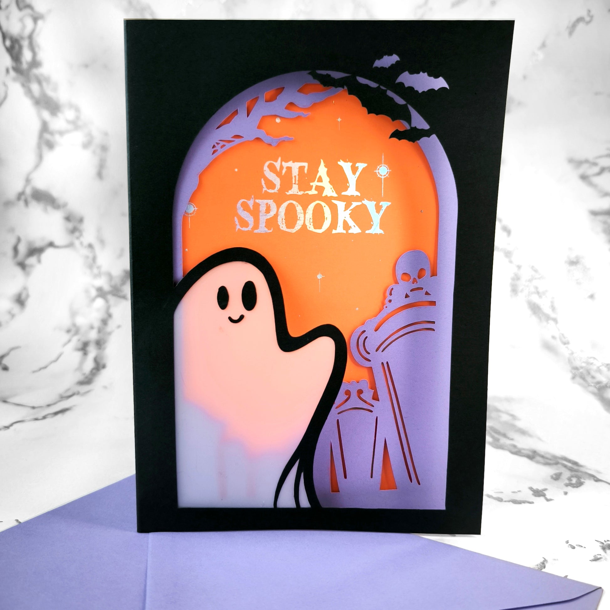 Handmade Halloween ghost greeting card with layered black, orange, and purple paper. Features a translucent ghost, holographic "Stay Spooky" lettering, and gothic graveyard scene.