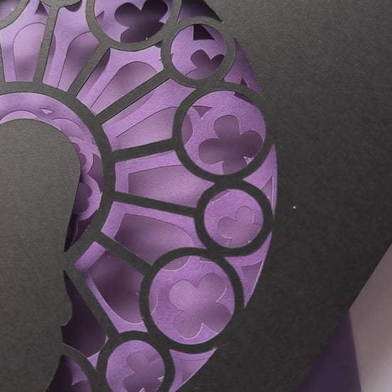 Handmade papercut greeting card, with a layered rose window in purple and black. Features a mother and baby silhouette in front of the gothic cathedral window design. Includes matching purple envelope.