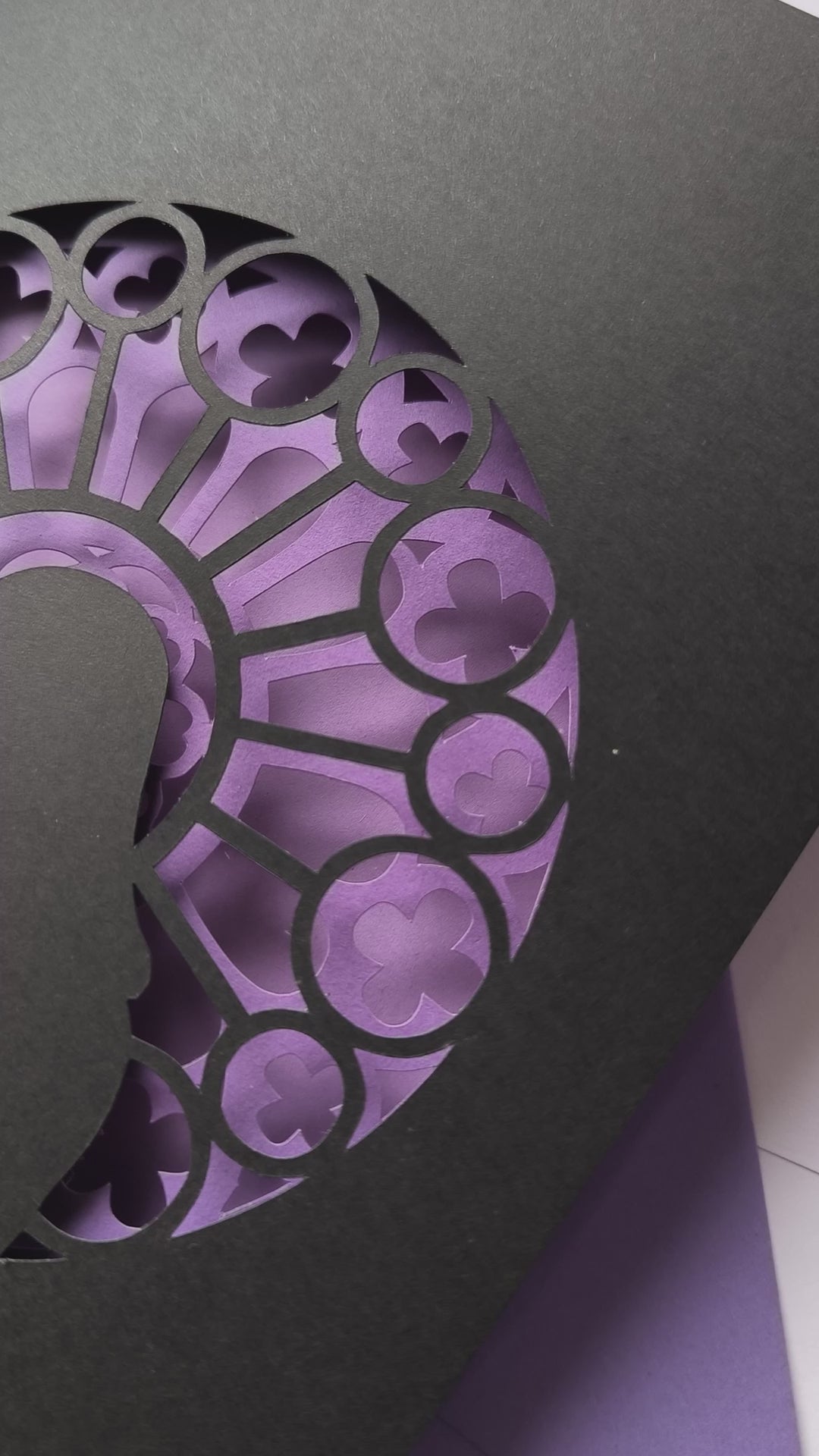 Handmade papercut greeting card, with a layered rose window in purple and black. Features a mother and baby silhouette in front of the gothic cathedral window design. Includes matching purple envelope.