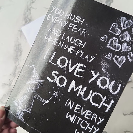 A black A5 greeting card with a chalkboard-style background, featuring a hand-drawn witch illustration casting a spell with floating love hearts. A sweet rhyming poem is written in chalk-style lettering. The card reads Happy Mother's Day inside and comes with an envelope.